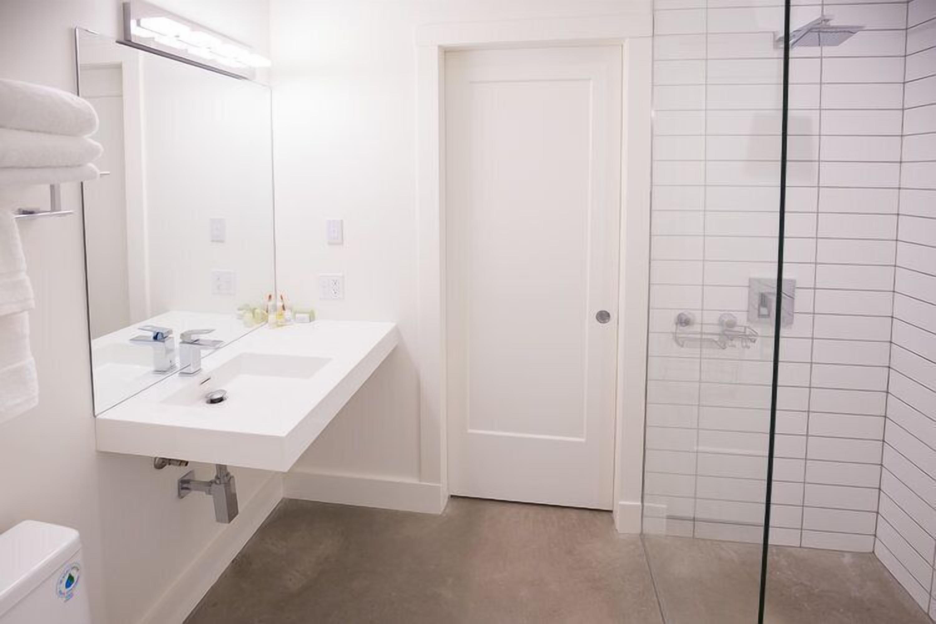 A bathroom with a white sink, mirror, and glass shower enclosure.