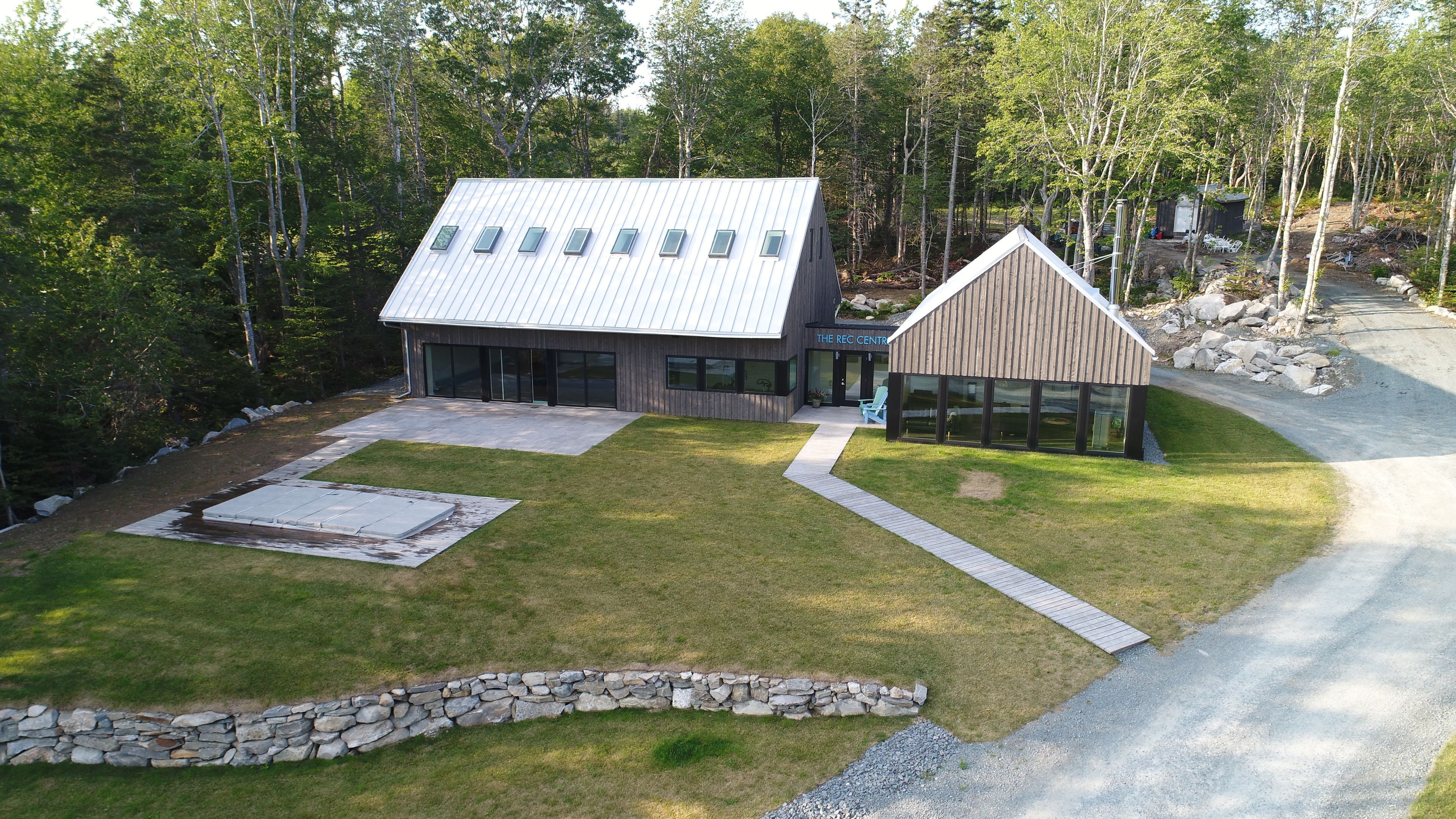 A modern building with a sloped roof, a stone wall, and a small wooden structure.