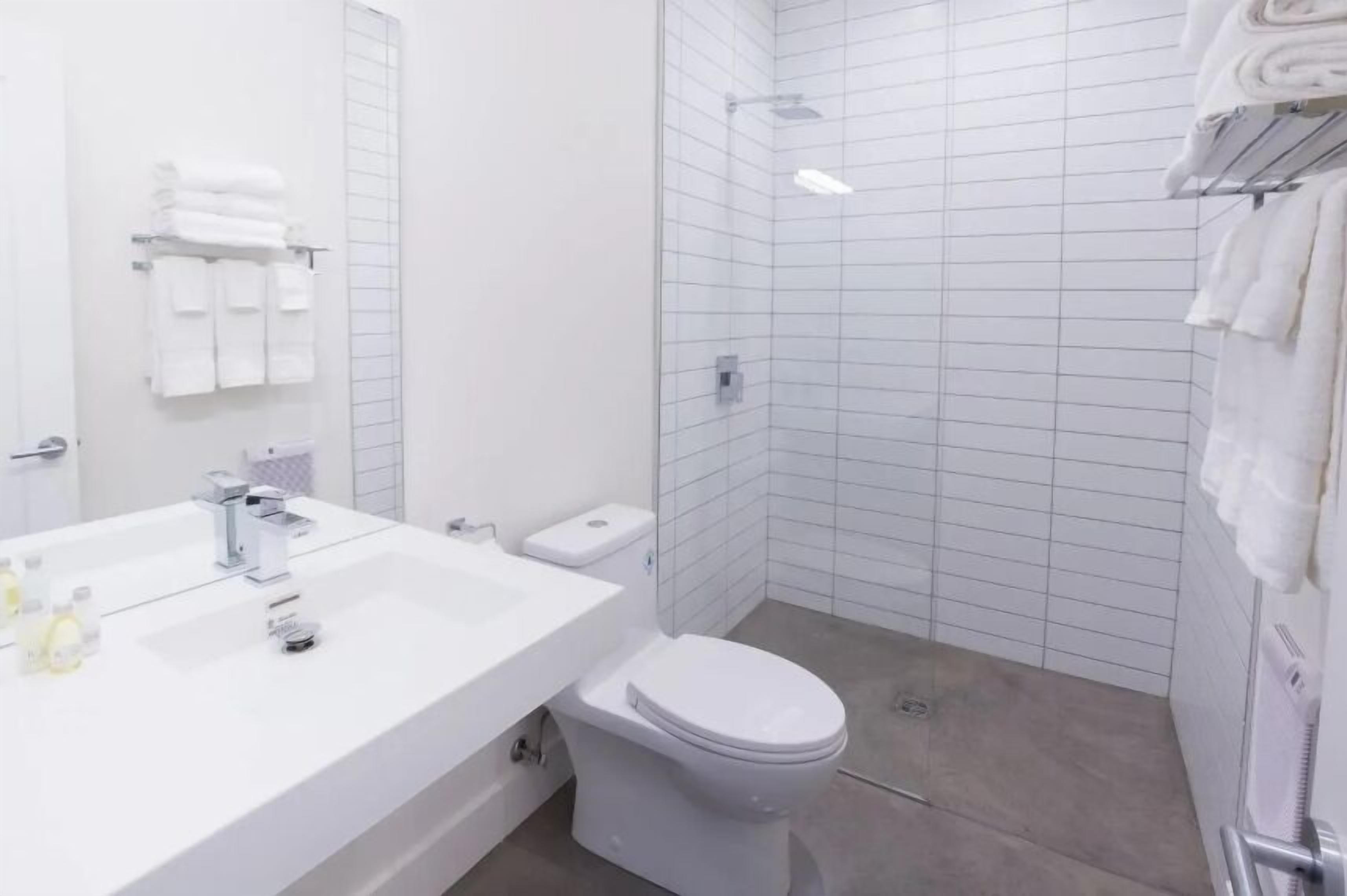 Un baño moderno con lavamanos, inodoro y ducha blancos.