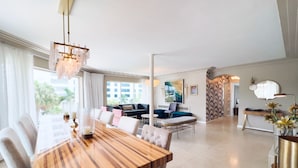 A spacious living area with a wooden dining table, comfortable seating, and a modern chandelier. - North Beach Hotel (Fort Lauderdale)