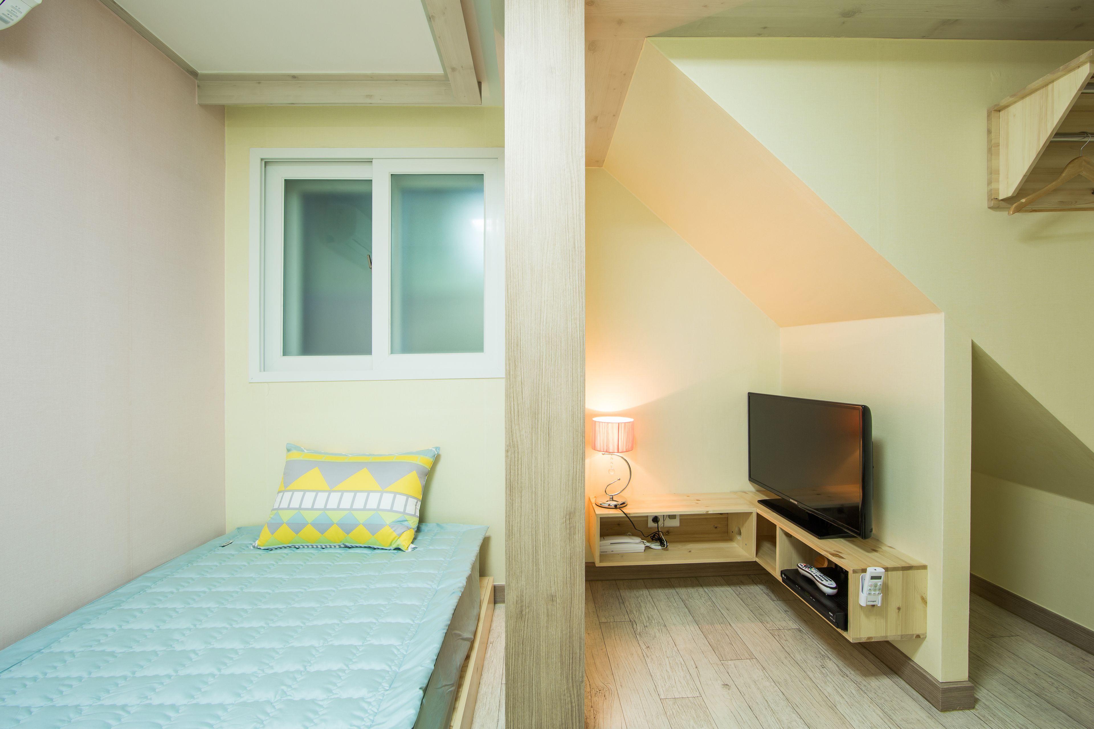 Un dormitorio con cama, televisor y ventana.