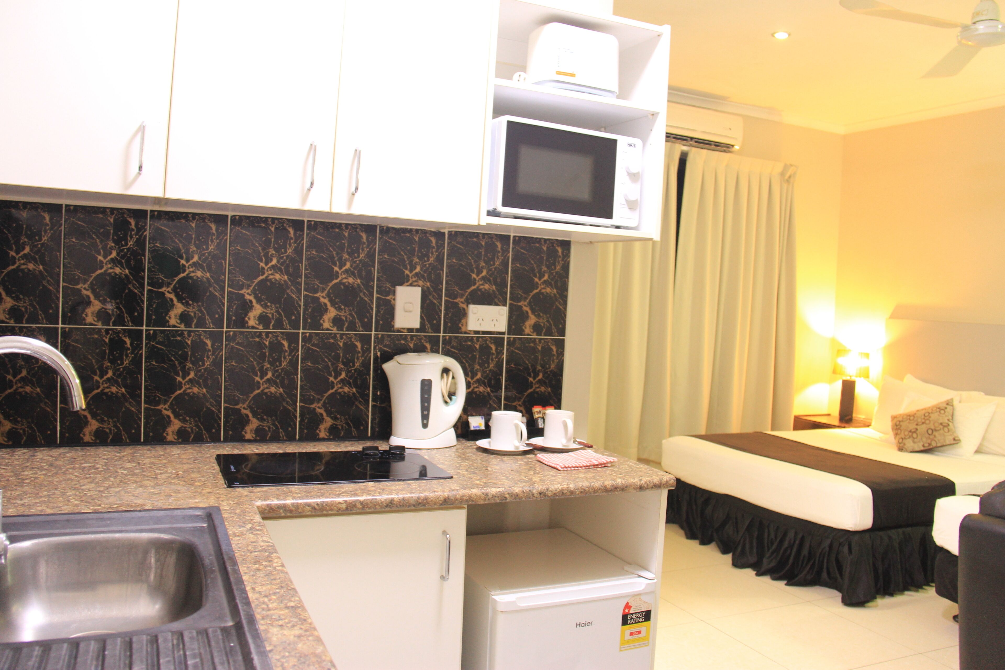 A compact hotel room with a kitchenette, including a microwave, kettle, and coffee maker.