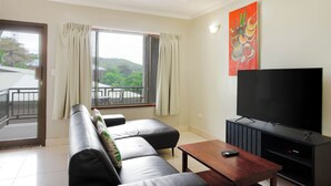 A living room with a sofa, a TV, and a balcony.