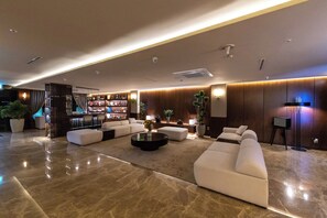 Un lobby moderno con área de descanso, mostrador de recepción y bar.