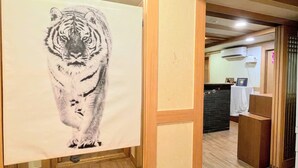 A hallway with a large tiger painting on the wall, wooden flooring, and a reception area in the background. - Cocoa Guesthouse (Seoul)