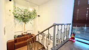 A staircase with a metal railing, a wooden bench, and a wall-mounted plant. - Cocoa Guesthouse (Seoul)