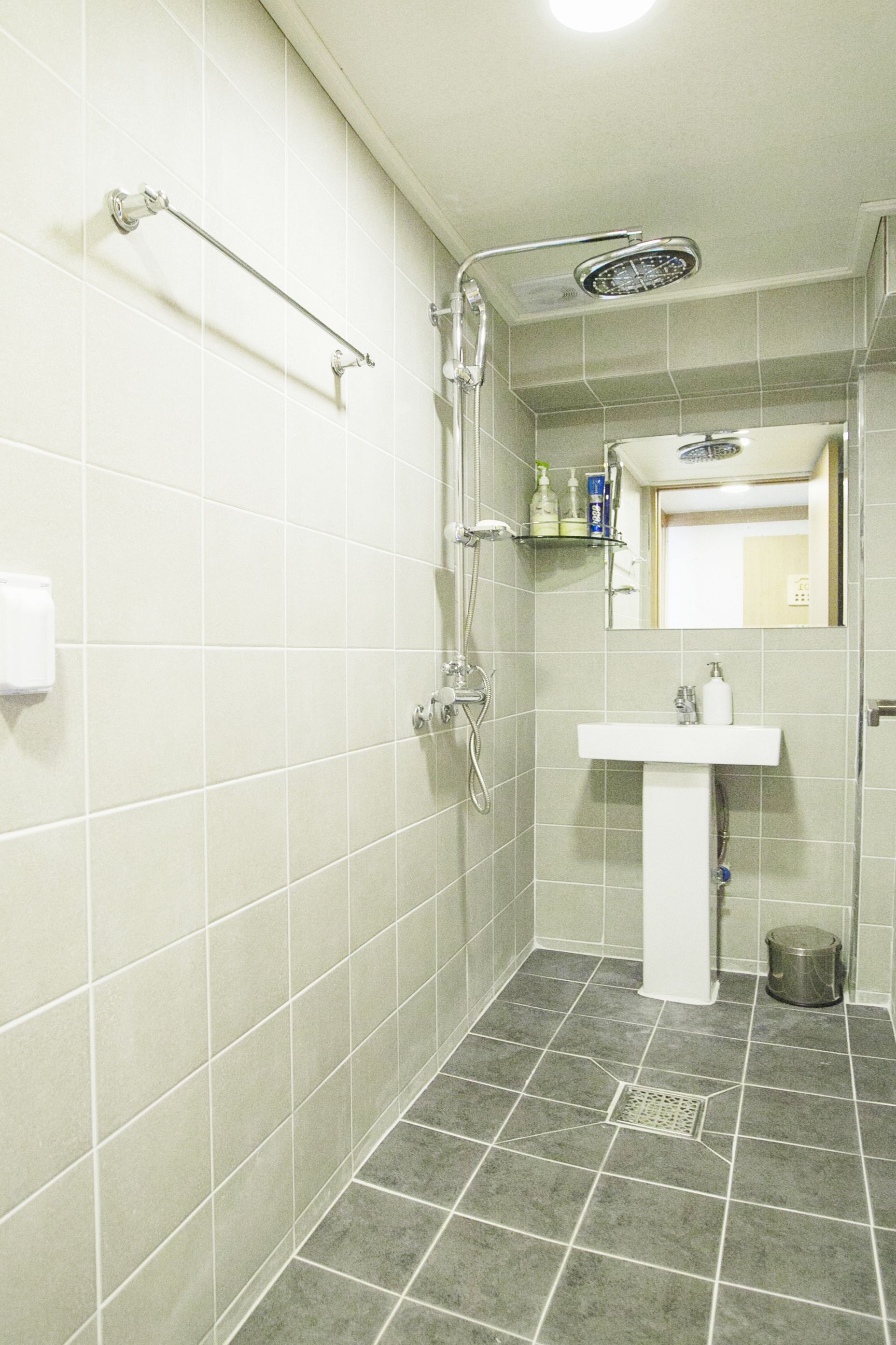 A bathroom with a shower, a sink, and a mirror.