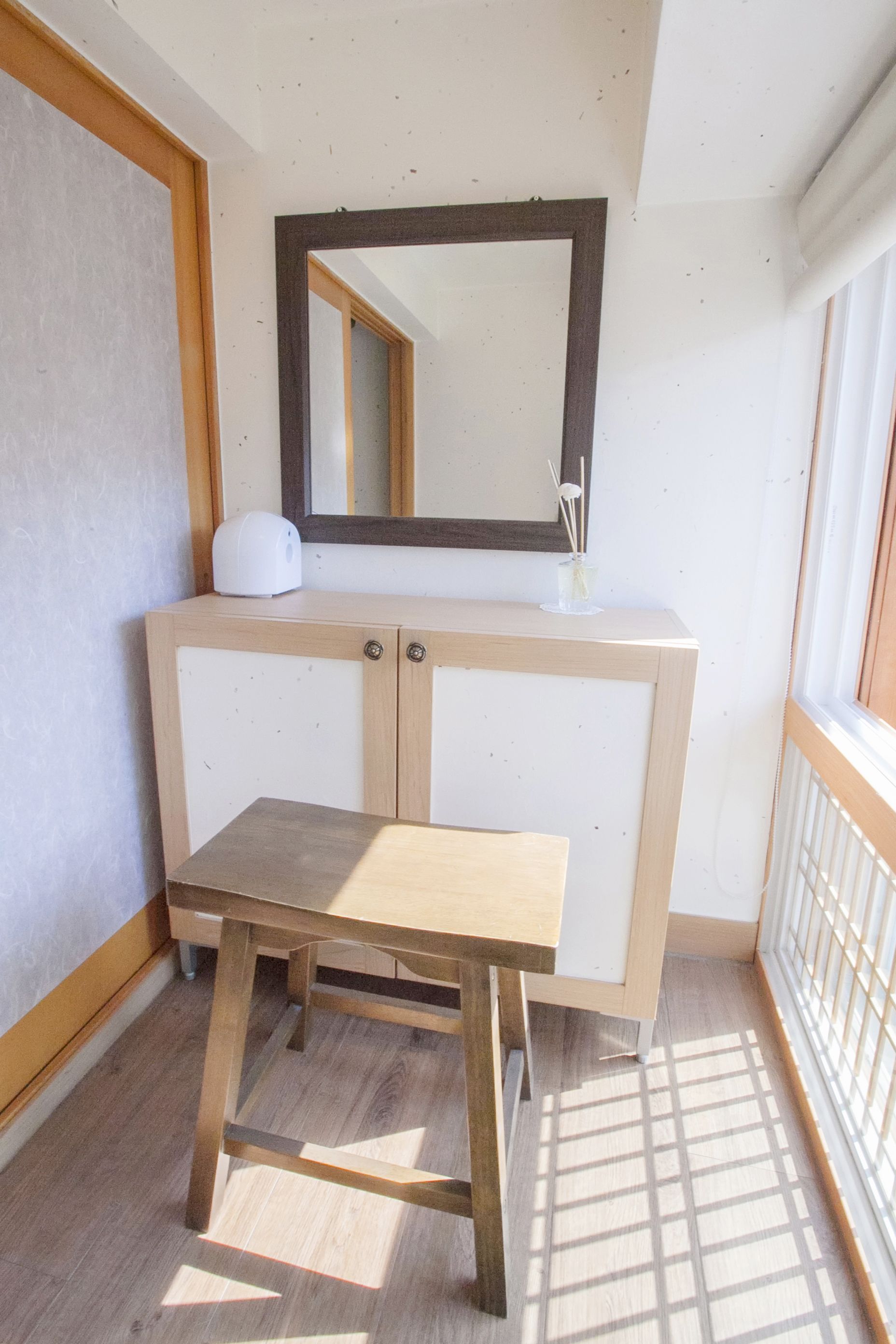 A small bathroom with a wooden bench, a mirror, and a white cabinet.