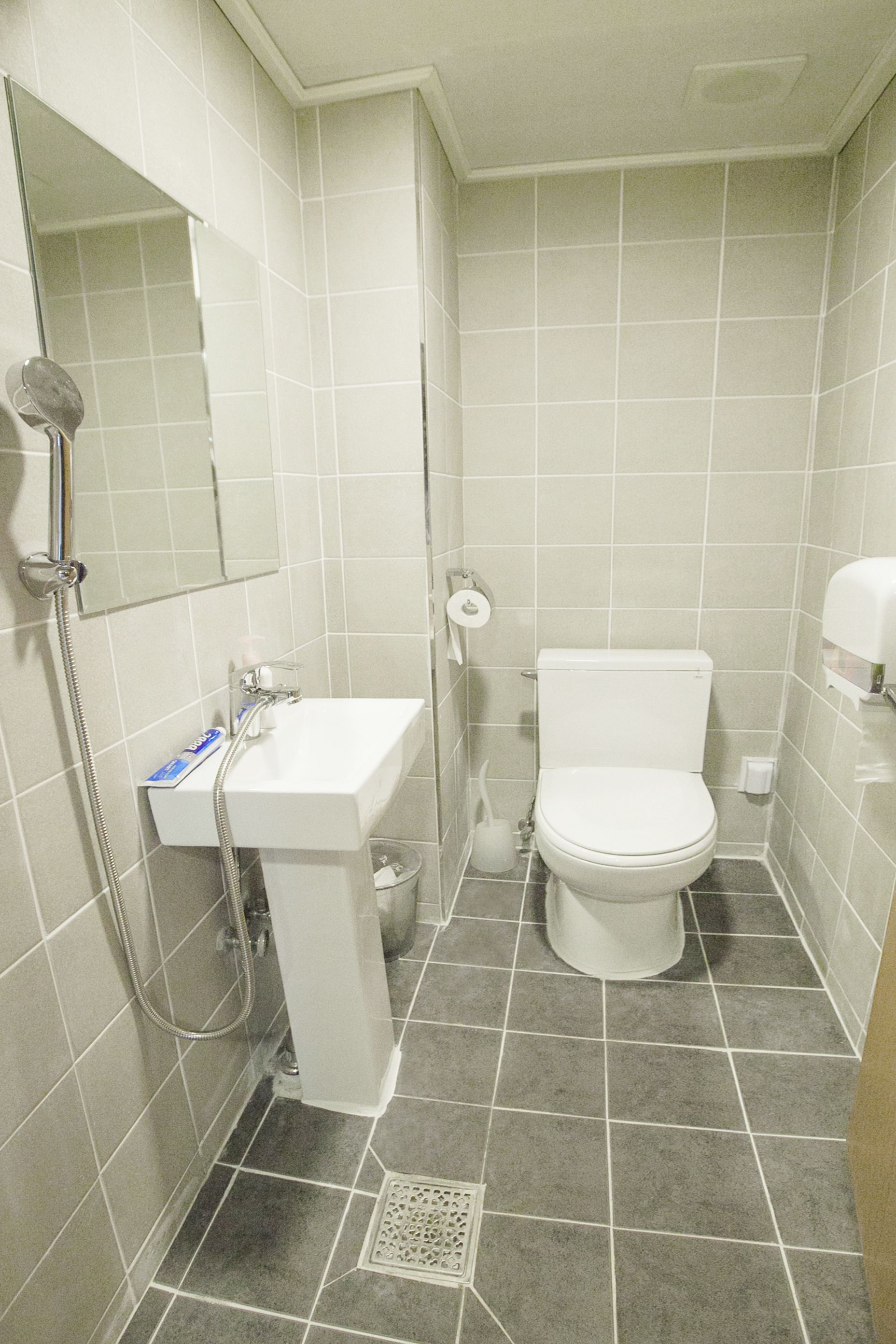 A small, clean bathroom with a toilet, sink, and shower.