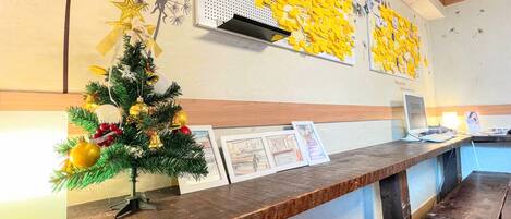 A reception desk with a small Christmas tree, framed pictures, and a wall with yellow notes.
