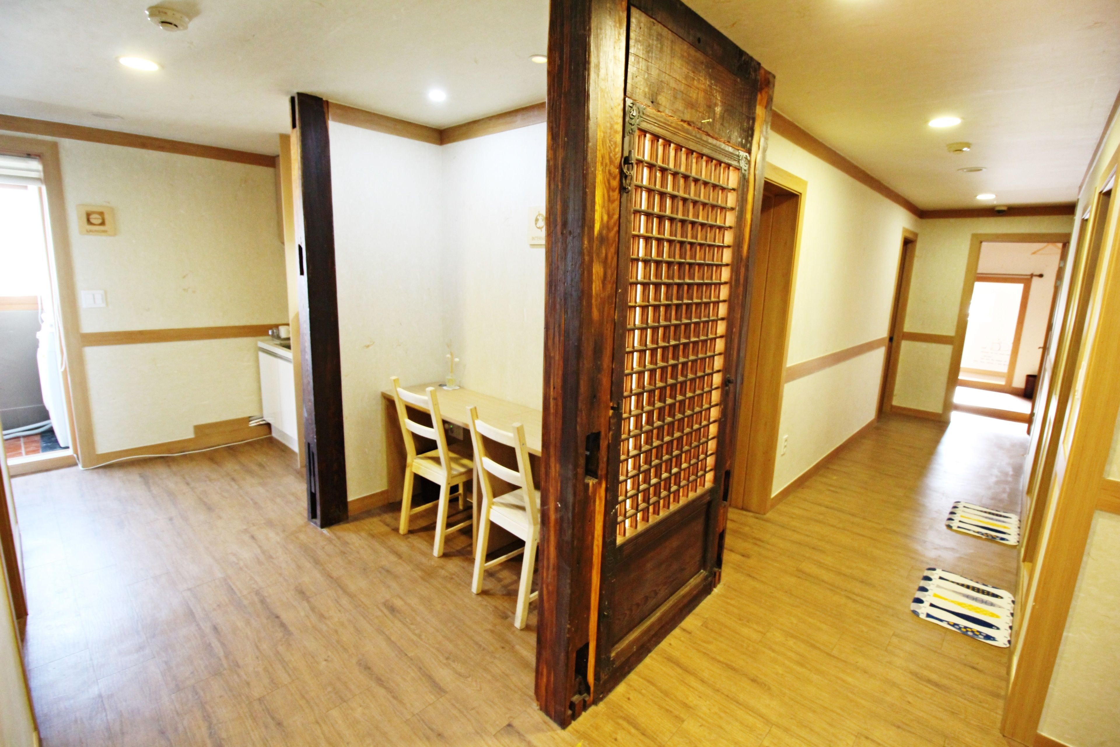 A room with a wooden floor, a dining table with chairs, and a door with a metal grid.