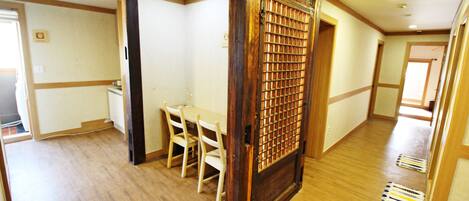 A room with a wooden floor, a dining table with chairs, and a door with a metal grid.