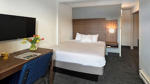 A hotel room with a bed, a desk with a chair, a television, and a lamp. - Golden North Inn (Fairbanks)