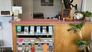 A reception desk with informational brochures, a clock, and a plant. - Golden North Inn (Fairbanks)