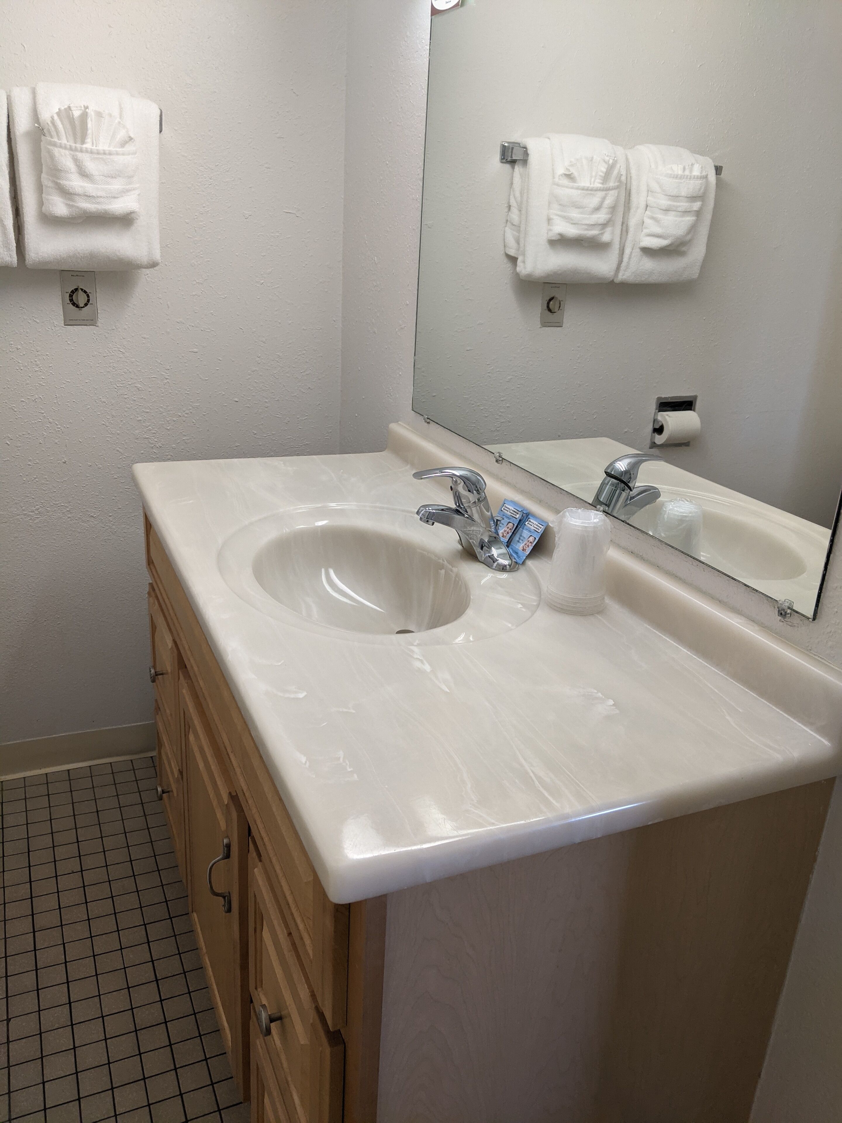 A bathroom with a white sink, two faucets, a mirror, and wooden cabinets.
