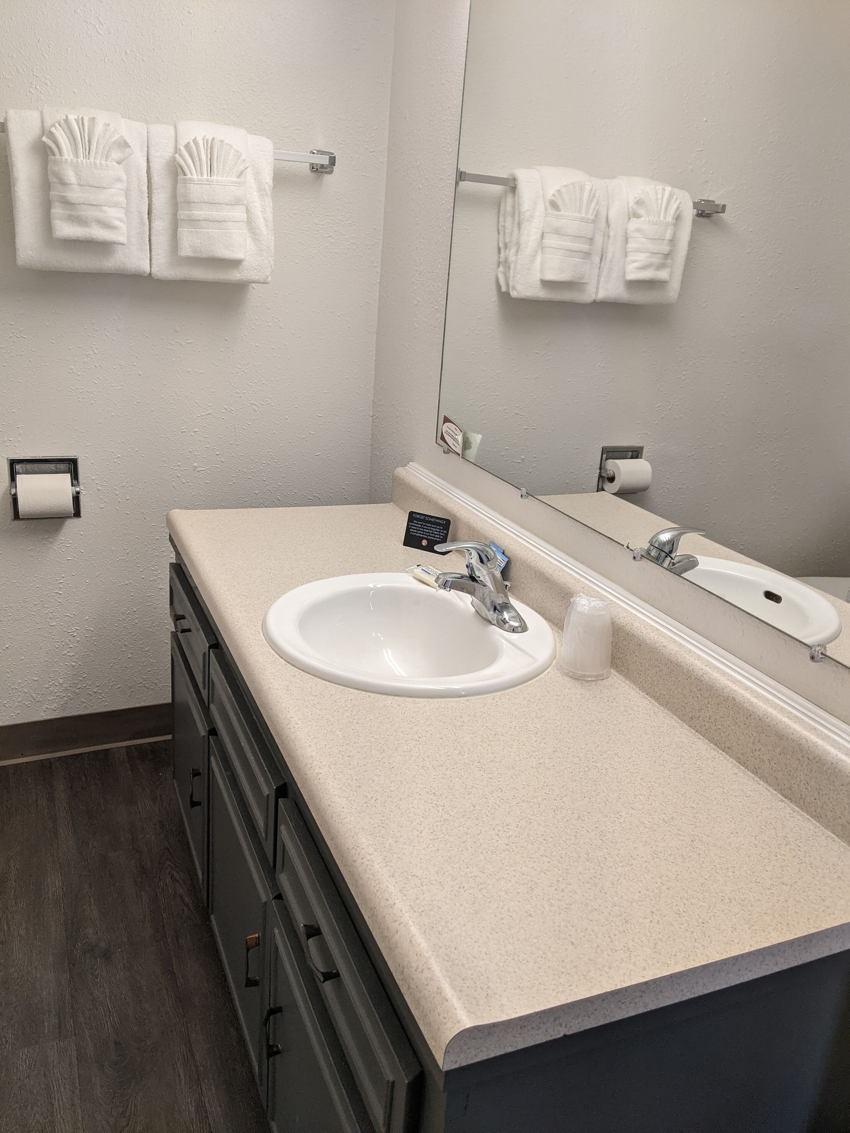 A bathroom with a white sink, a mirror, and two towels hanging on towel racks.
