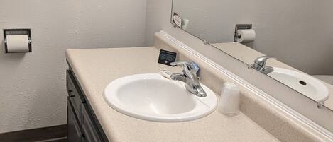 A bathroom with a white sink, a mirror, and two towels hanging on towel racks.