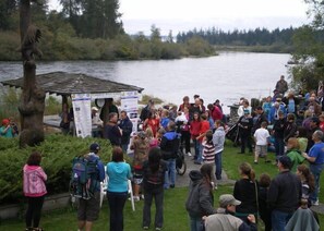 A group of people gathered outdoors near a body of water, with a small structure that appears to be a gazebo or information booth. - Campbell River Lodge by Riverside (Campbell River)