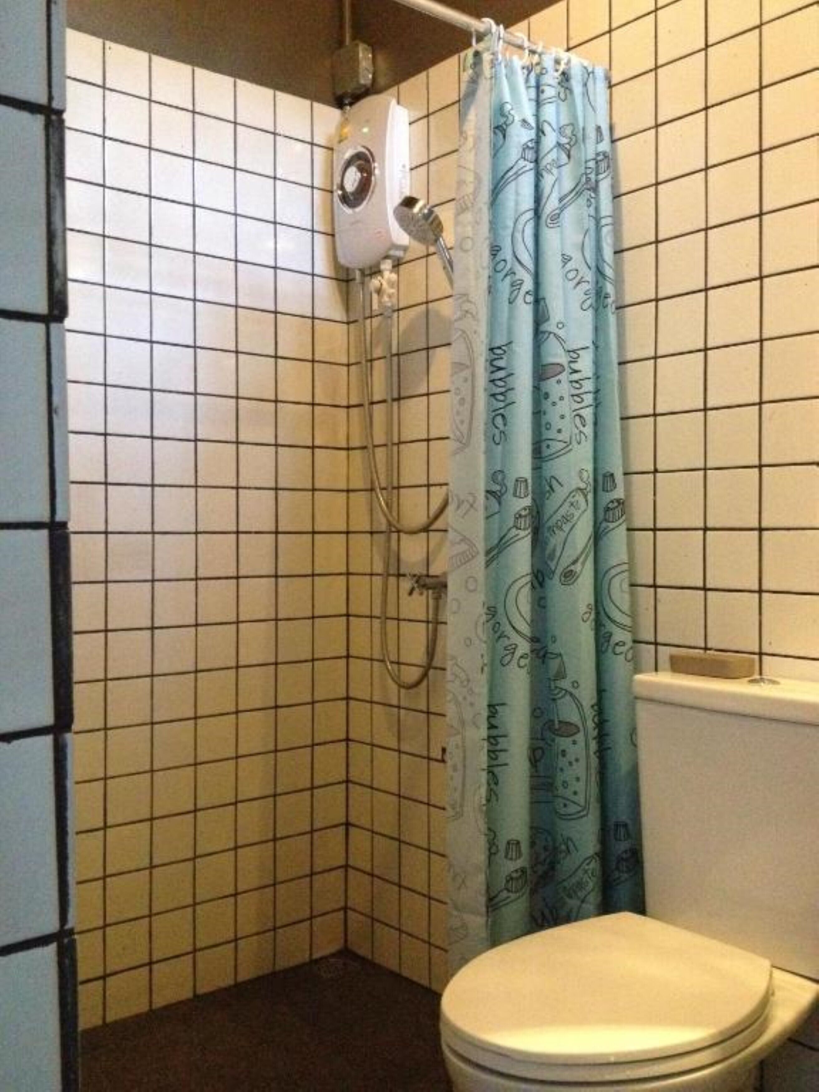 Ein kleines Badezimmer mit Toilette, einer Dusche mit blauer Duschvorhang und einem Wandheizgerät.