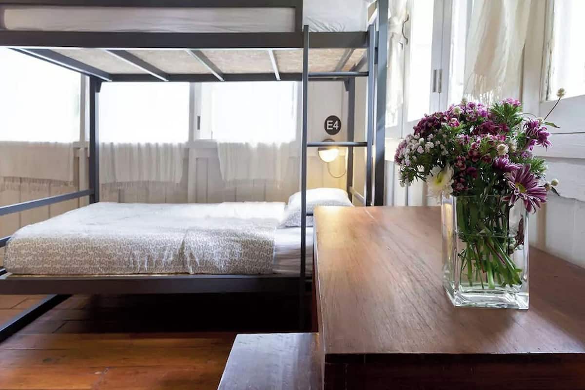 A bunk bed room with a wooden table and a vase of flowers.