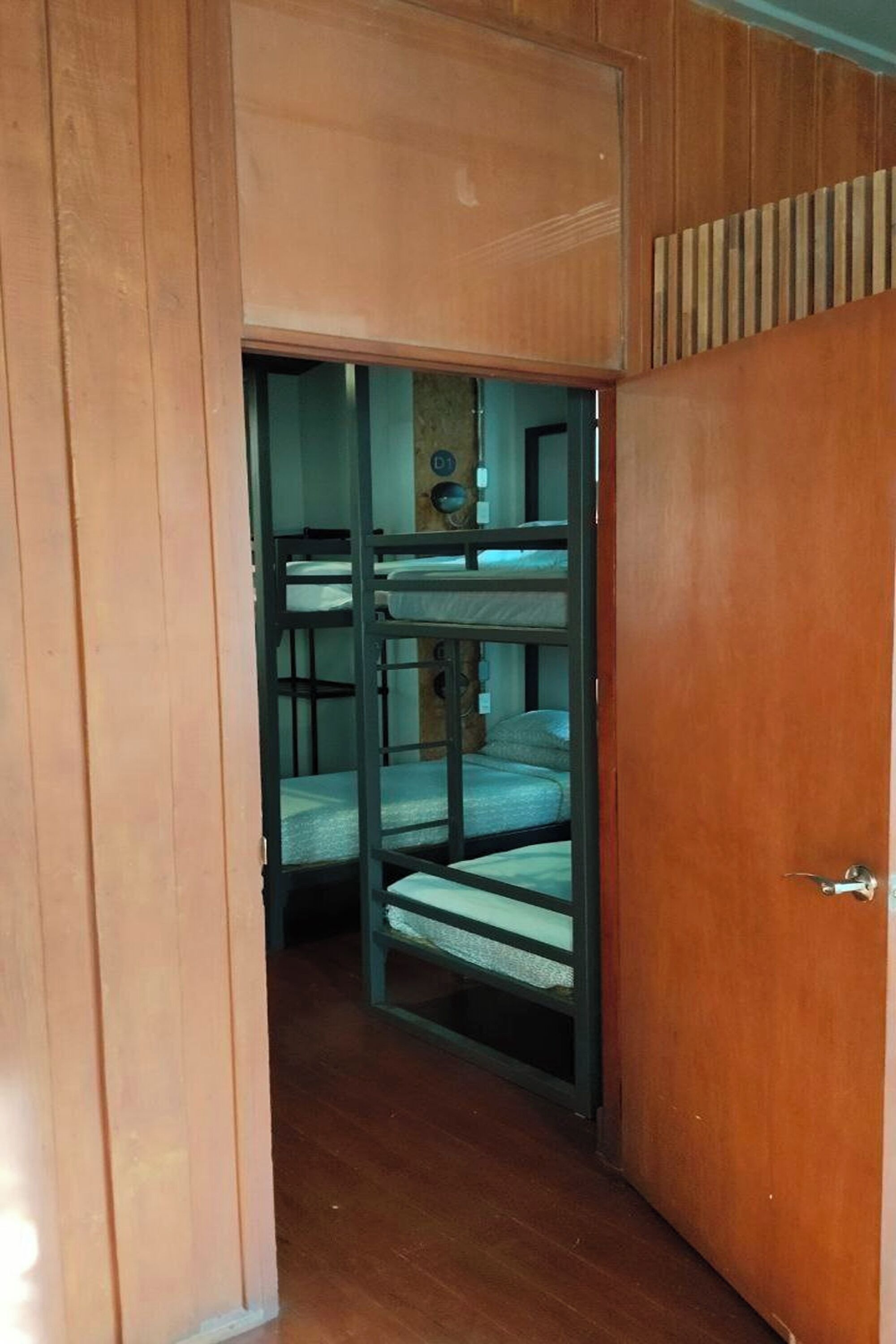 A wooden door leading to a room with bunk beds.