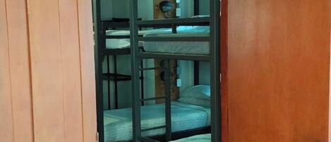 A wooden door leading to a room with bunk beds.