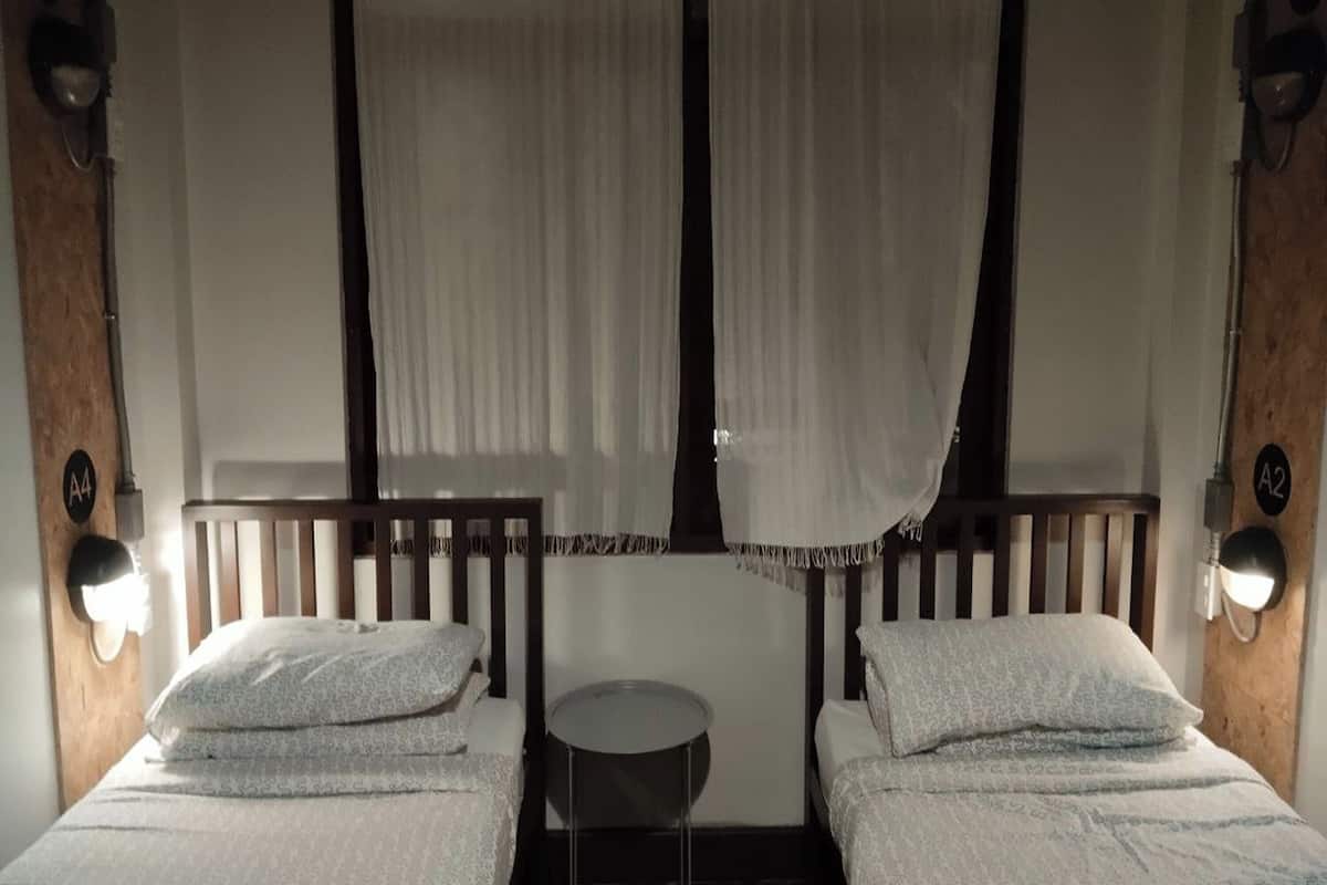 A room with two beds, a small round table, and curtains.
