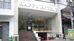Exterior del Hotel Happy, con entrada despejada, escalones que conducen a la puerta y un cartel con información sobre precios.
