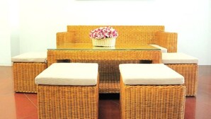 A wicker sofa set with cushions, a glass-top coffee table, and a framed floral painting on the wall. - Hanoi New Hotel (Hanoi)