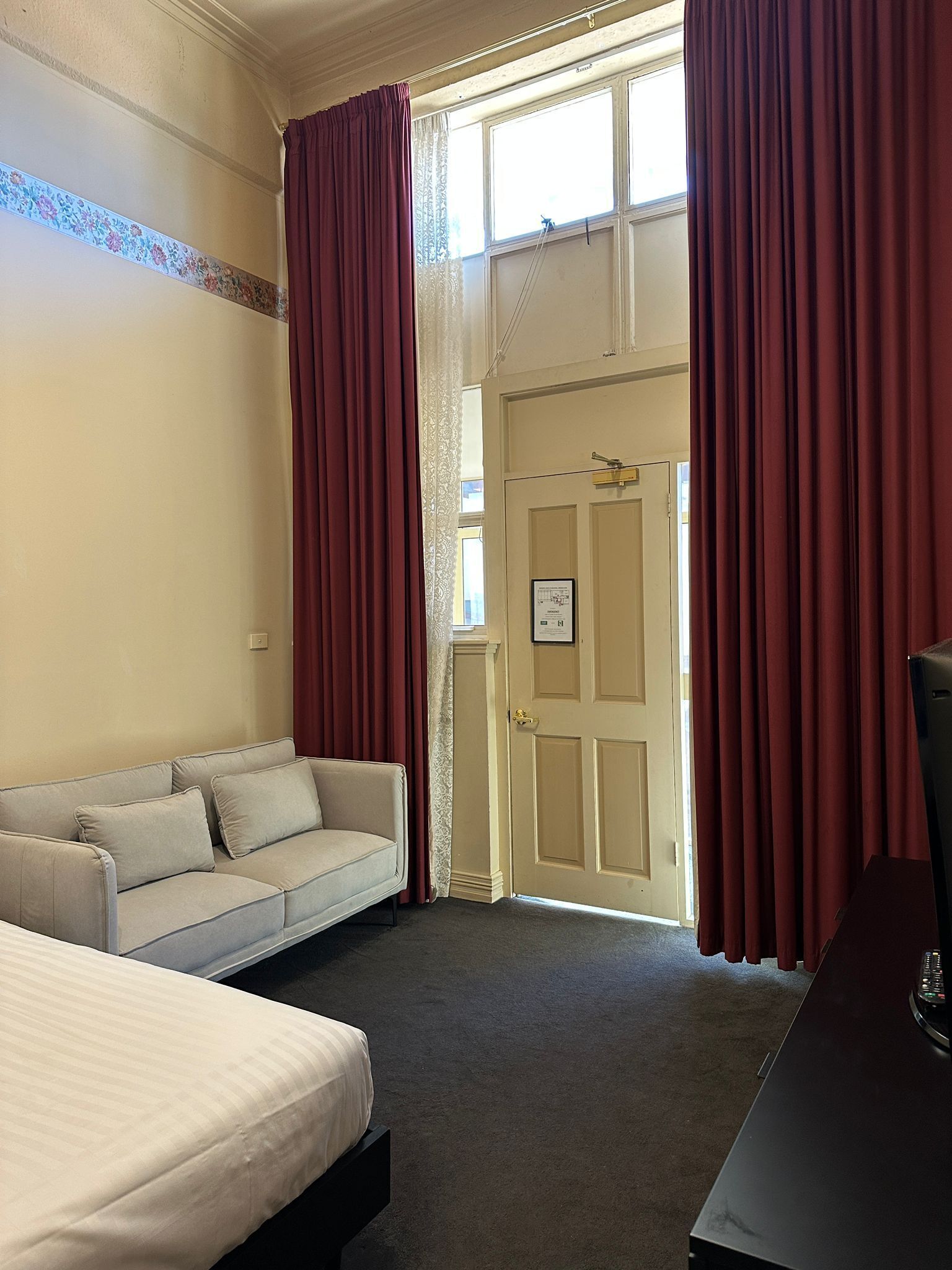 Een hotelkamer met een bed, een bank, een bureau en een deur naar buiten.