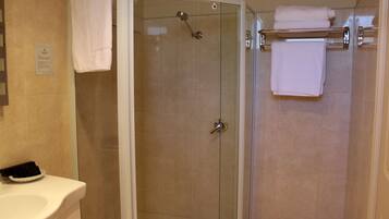 Un baño moderno con ducha de vidrio, lavamanos blanco y toallero con toallas dobladas.