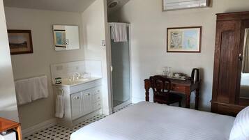 A hotel room with a large bed, a bathroom with a sink and mirror, a wooden desk, and a map on the wall.