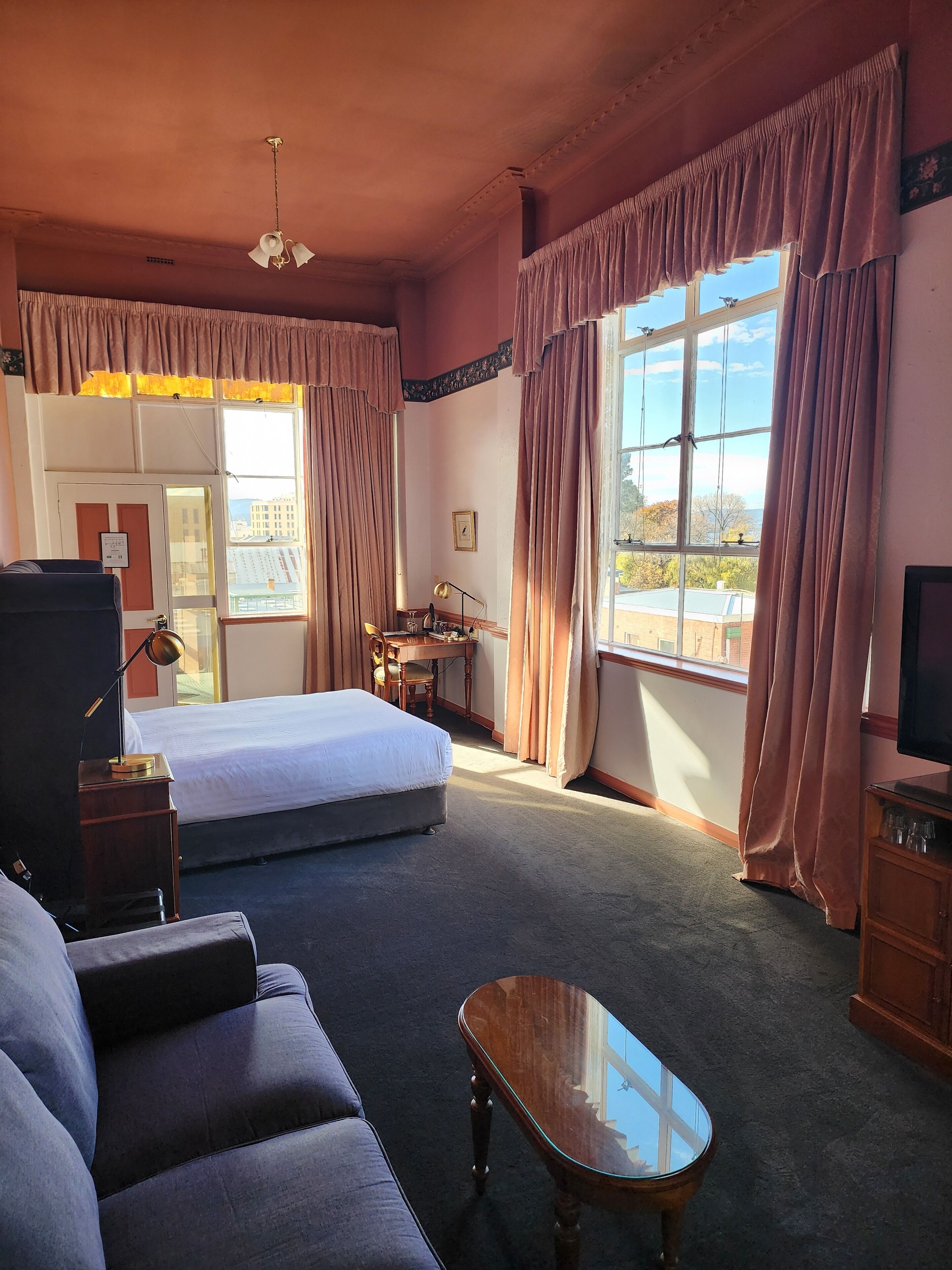 A hotel room with a bed, sofa, desk, and a TV.