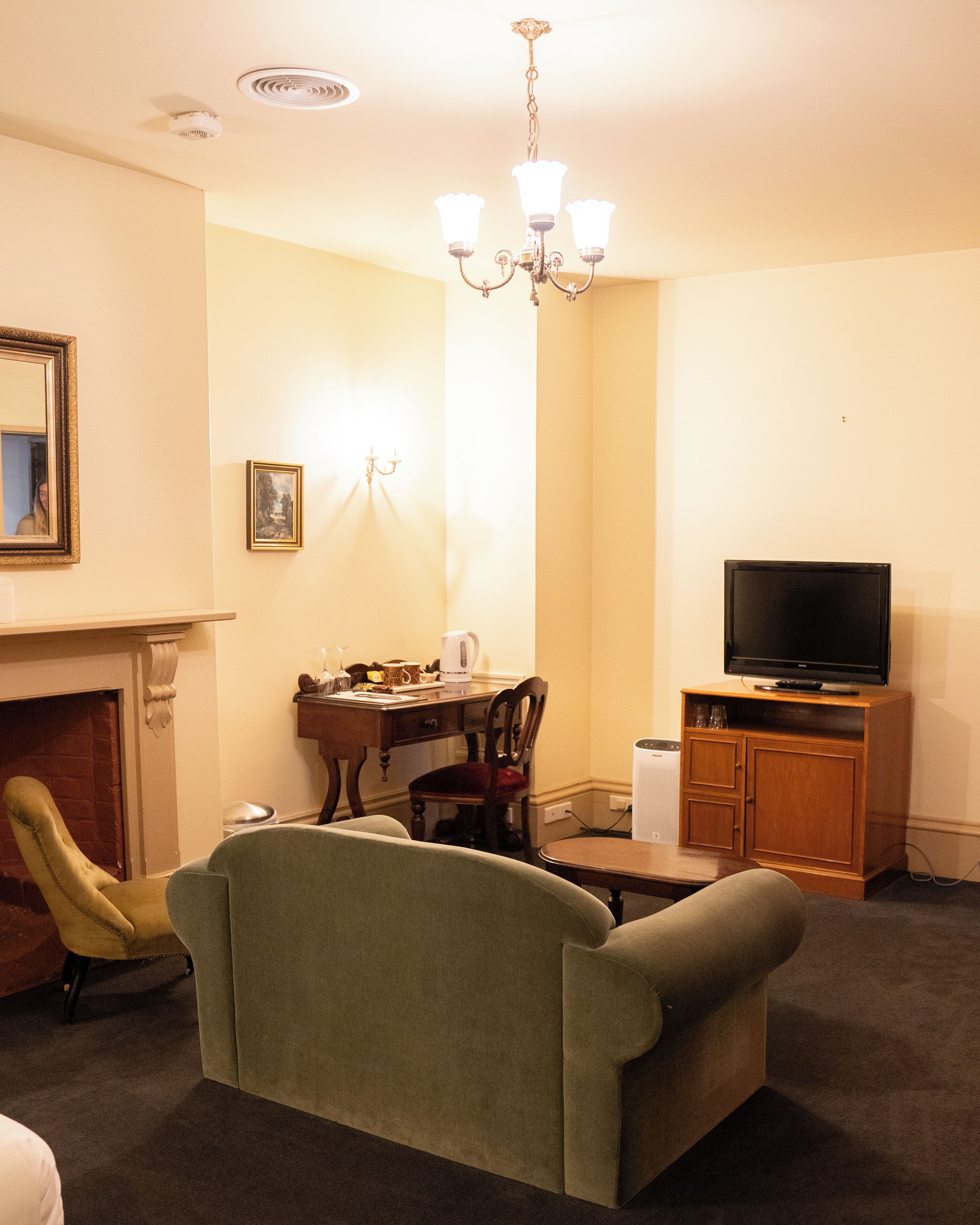 Una sala de estar con sofá, televisor sobre un mueble de madera, chimenea y comedor con mesa y sillas.