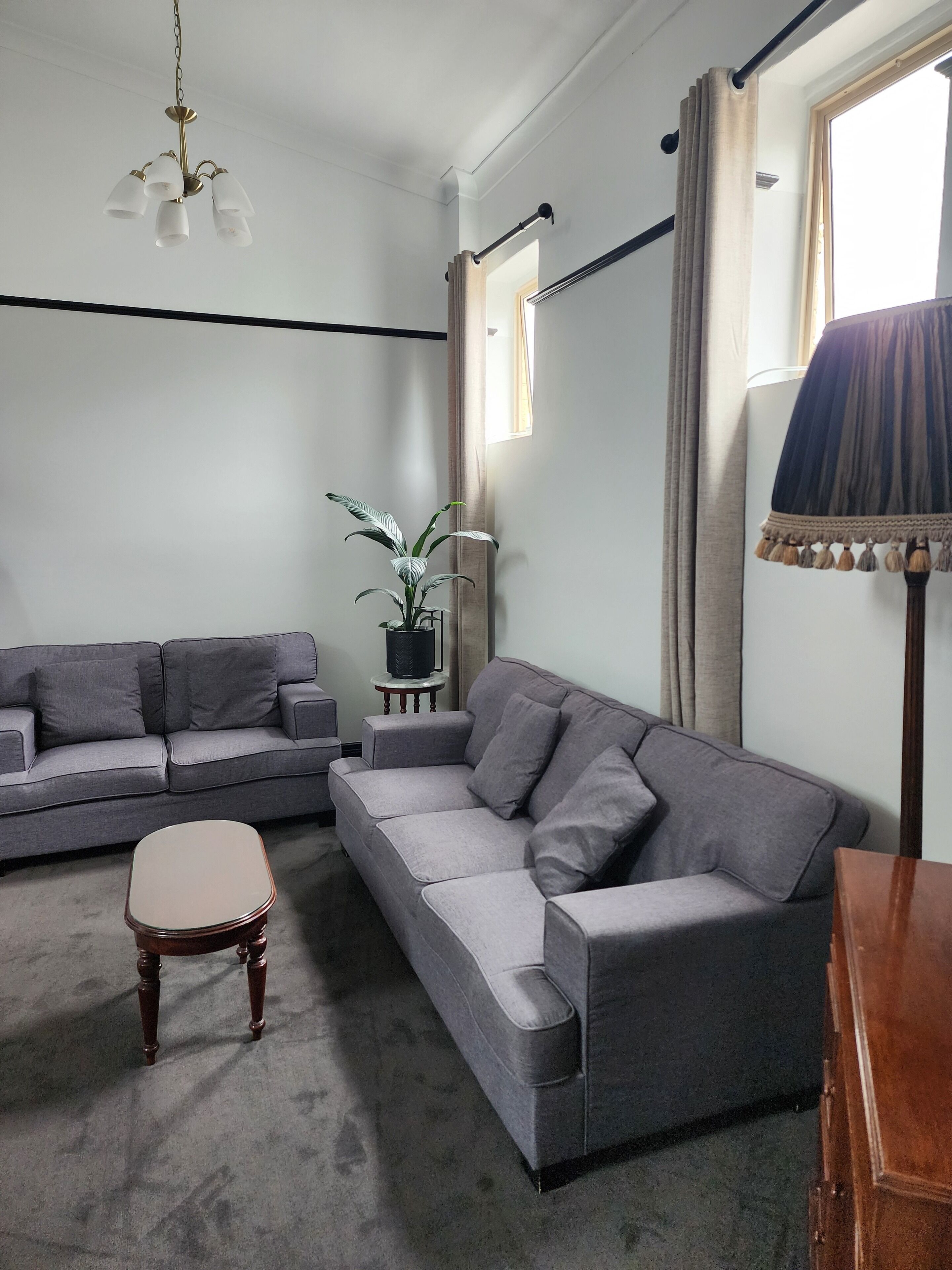 A modern living room with a grey sofa set, a small wooden table, and a potted plant.