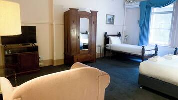 A hotel room with a bed, a sofa, a TV, a wardrobe, and a mirror.
