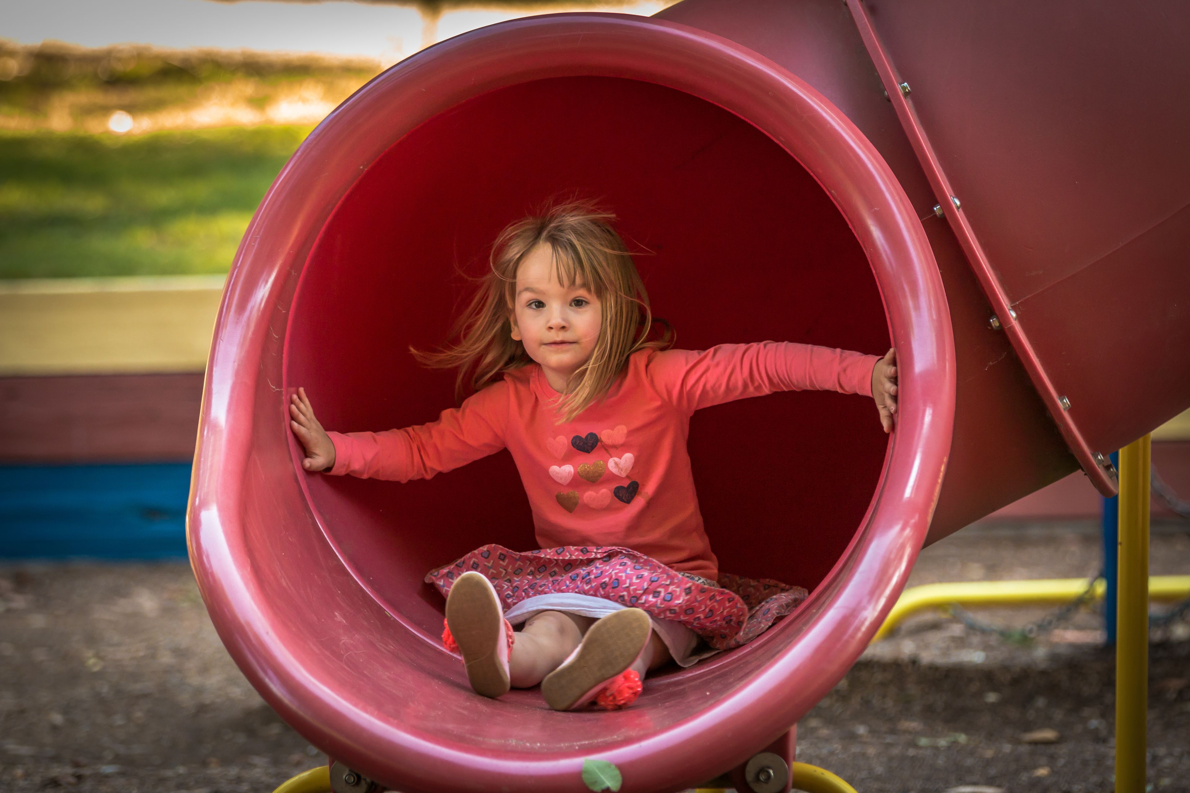 A child in a red slide at a playground.