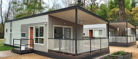 A single-story mobile home with a covered porch, a fenced yard, and a small garden area.