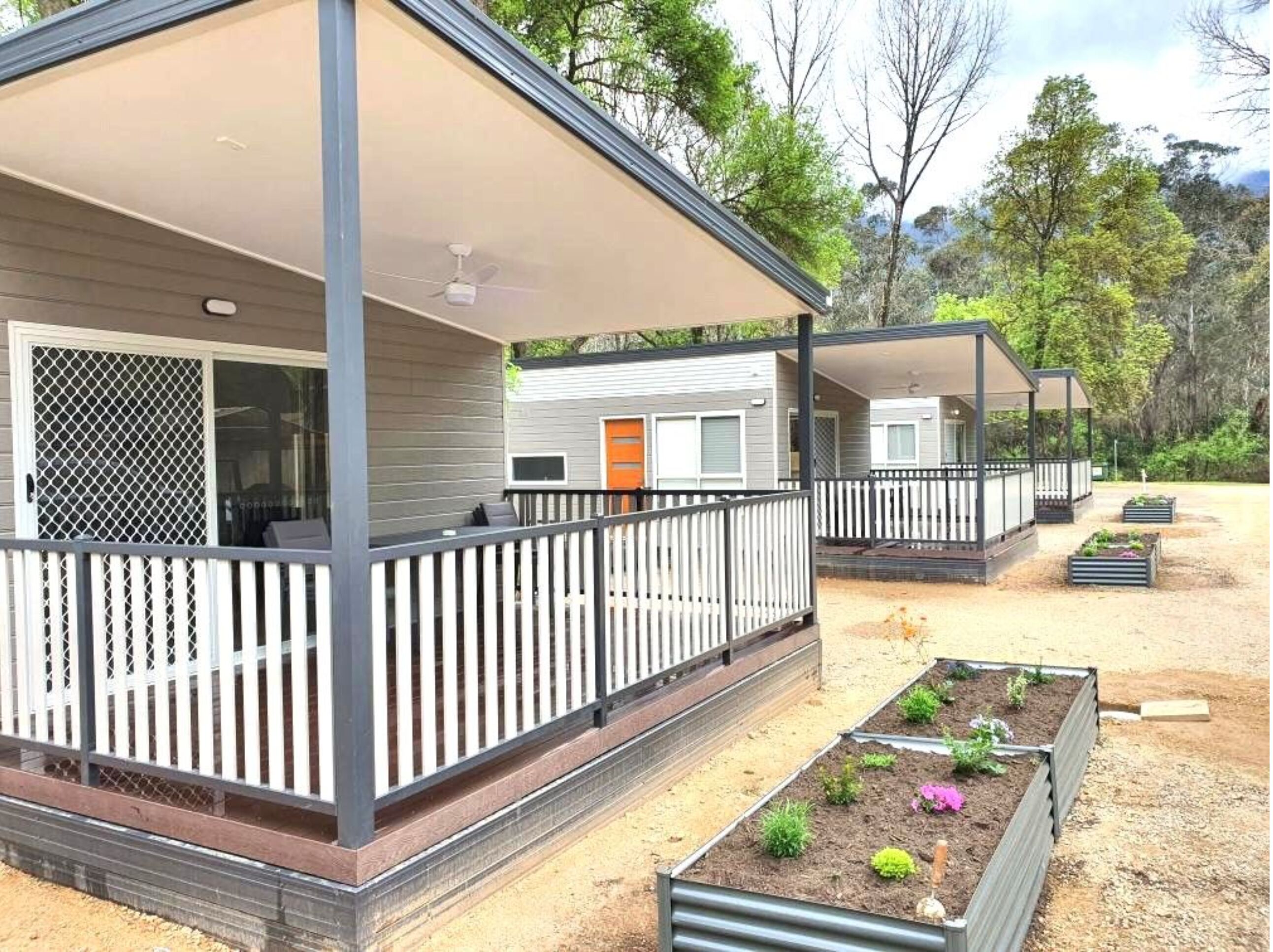 A modern RV-style mobile home with a covered porch and outdoor seating area.