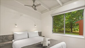 A modern bedroom with a large bed, a ceiling fan, and a window with a view of greenery. - Discovery Parks - Bright (Freeburgh)