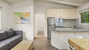 A modern kitchen with white cabinets, stainless steel appliances, and a wooden dining table. - Discovery Parks - Bright (Freeburgh)
