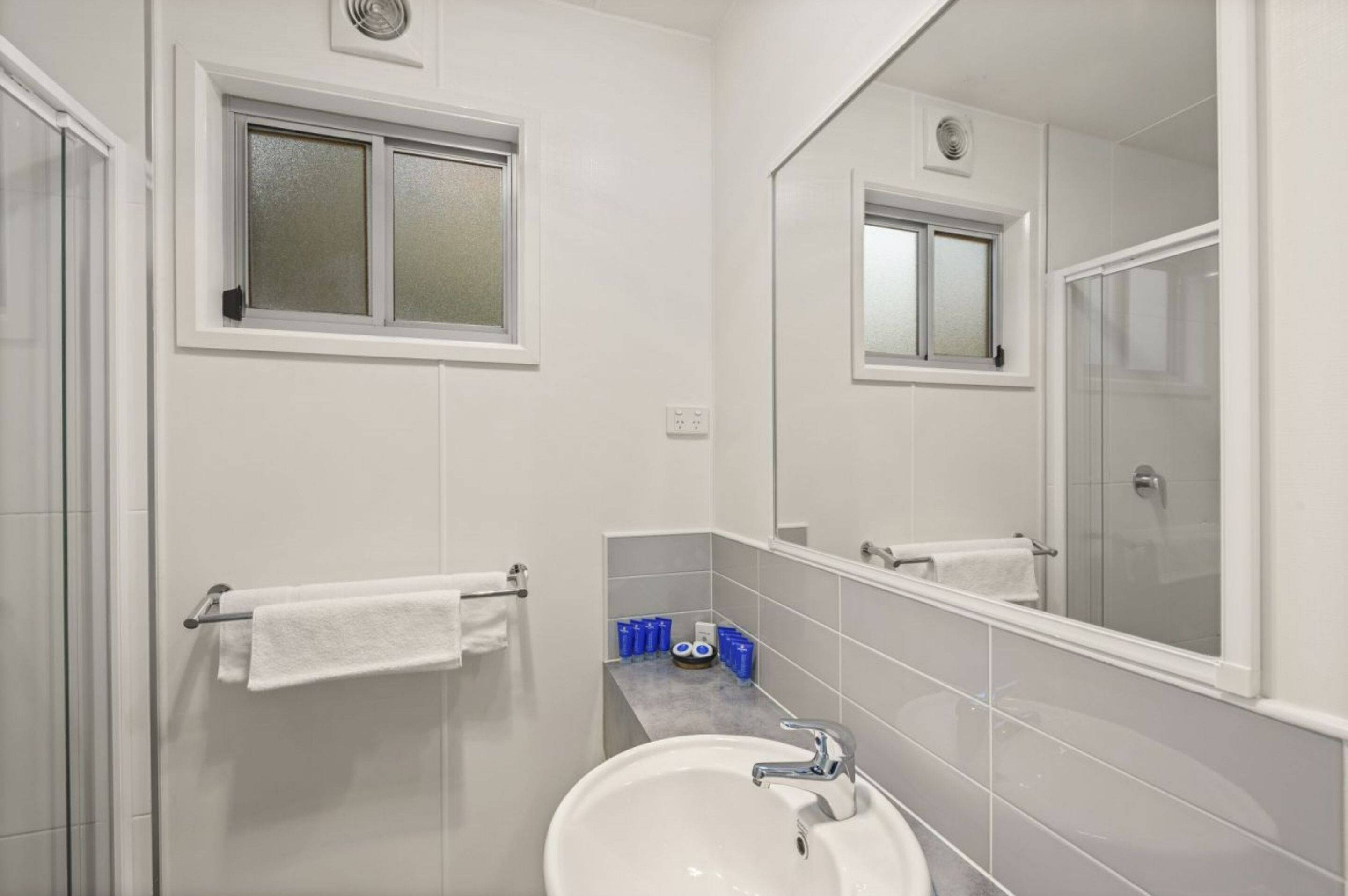 A modern bathroom with a white sink, a mirror, and a towel rack.
