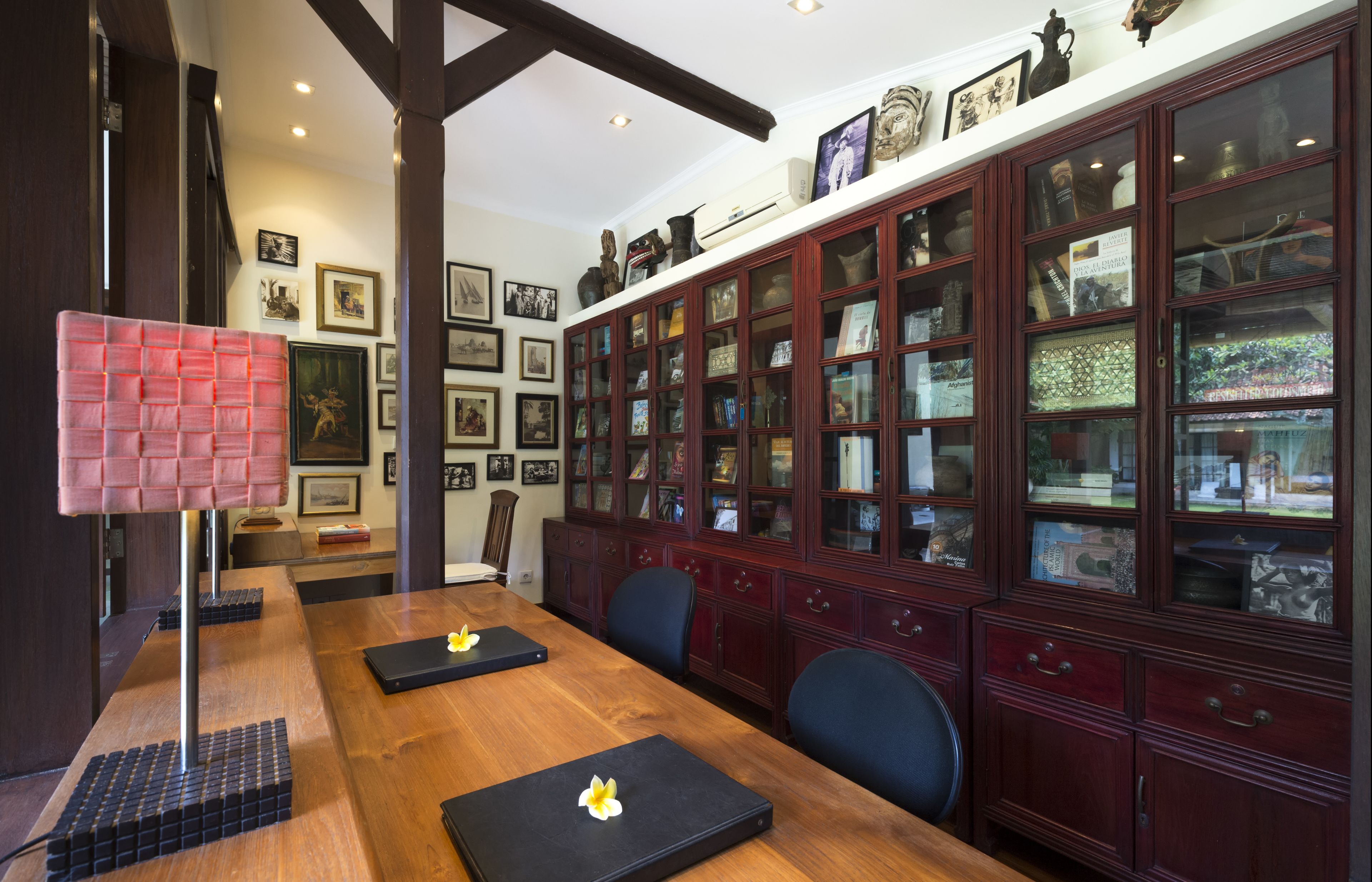 A conference room with a long wooden table, black chairs, and a red lamp.