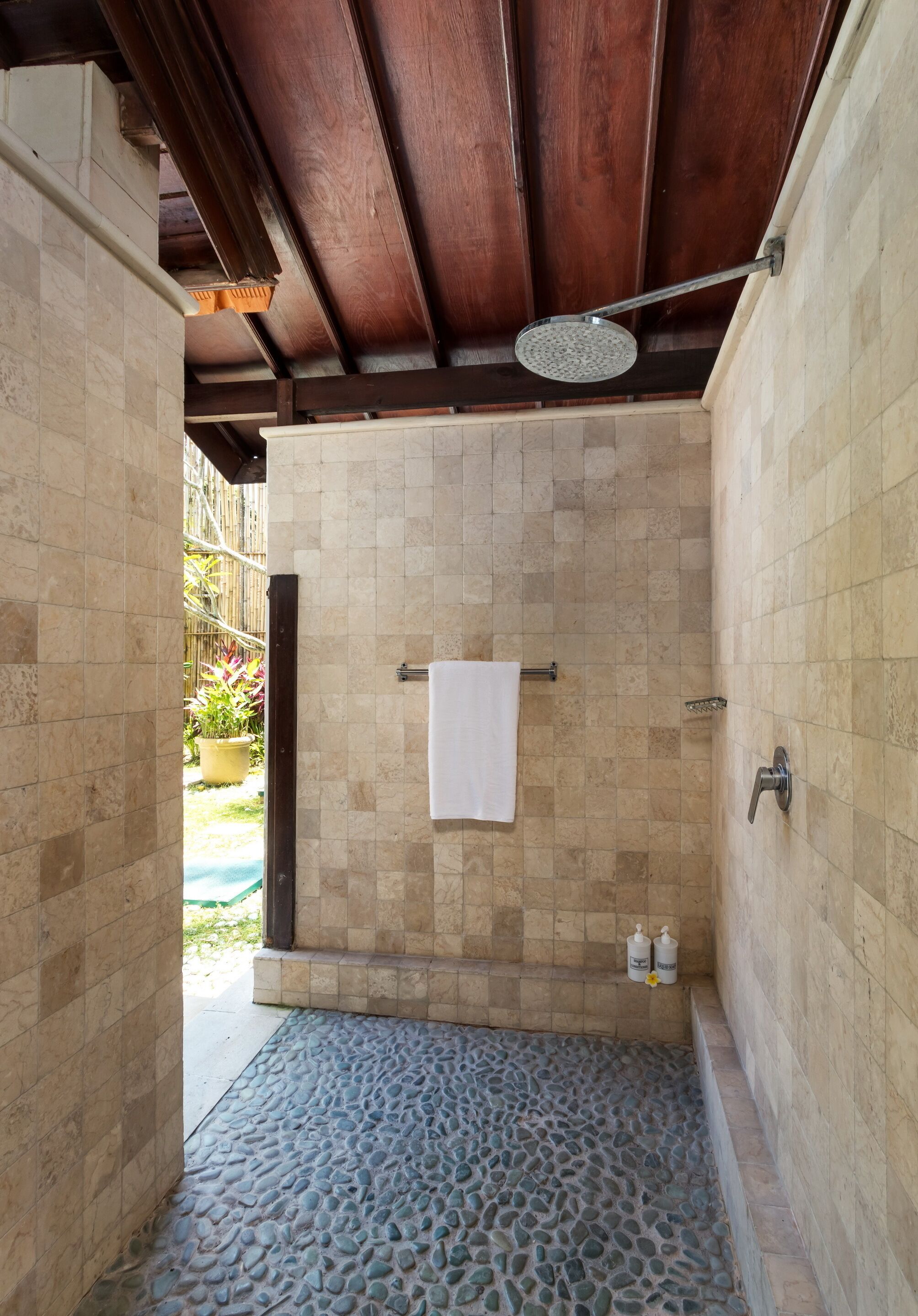 Un espace douche avec un sol carrelé, une serviette suspendue à un porte-serviettes et une pomme de douche.