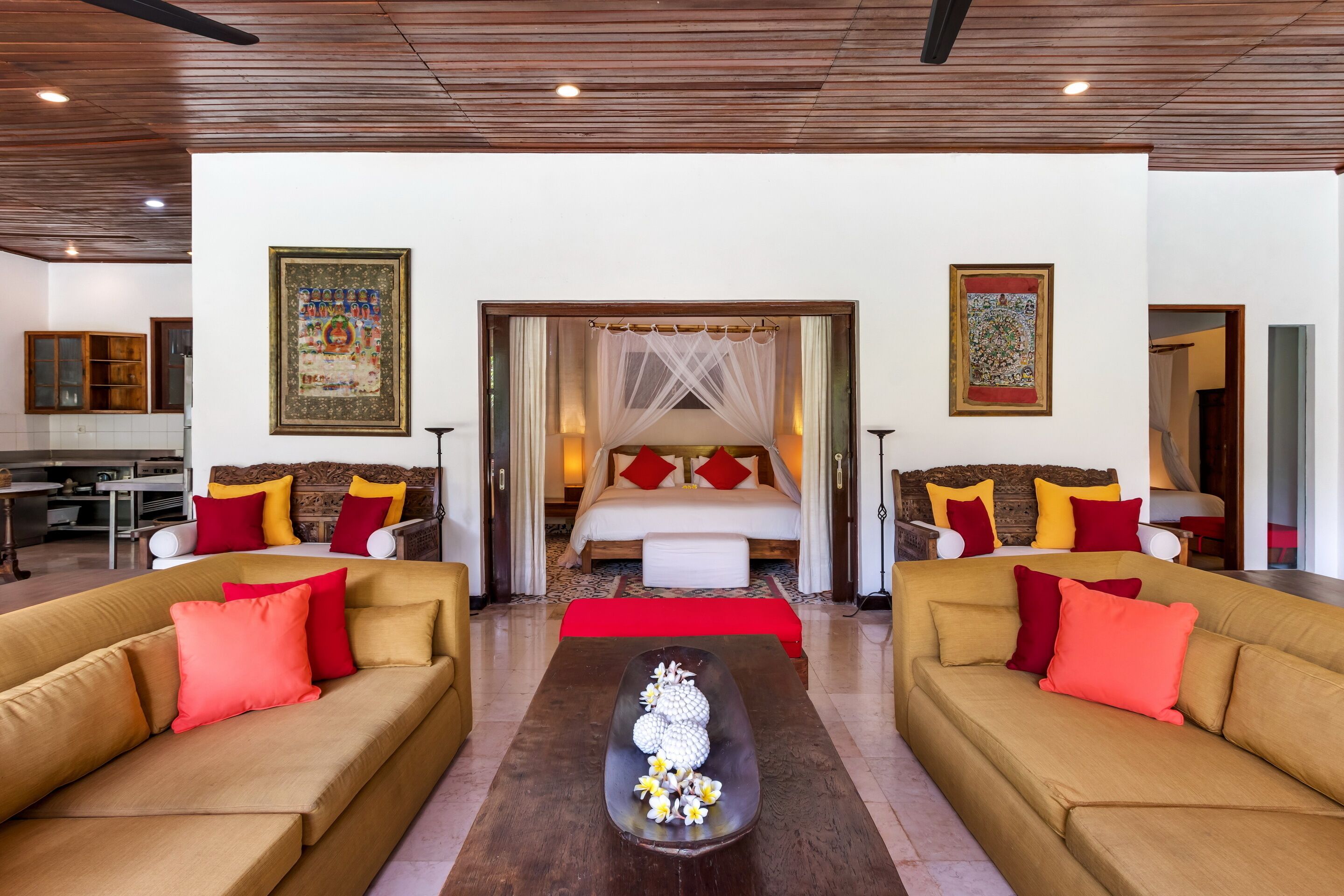 A hotel room with a large bed, two sofas, a coffee table, and artwork on the walls.