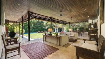 A spacious living area with a wooden ceiling, a large rug, and a sofa.