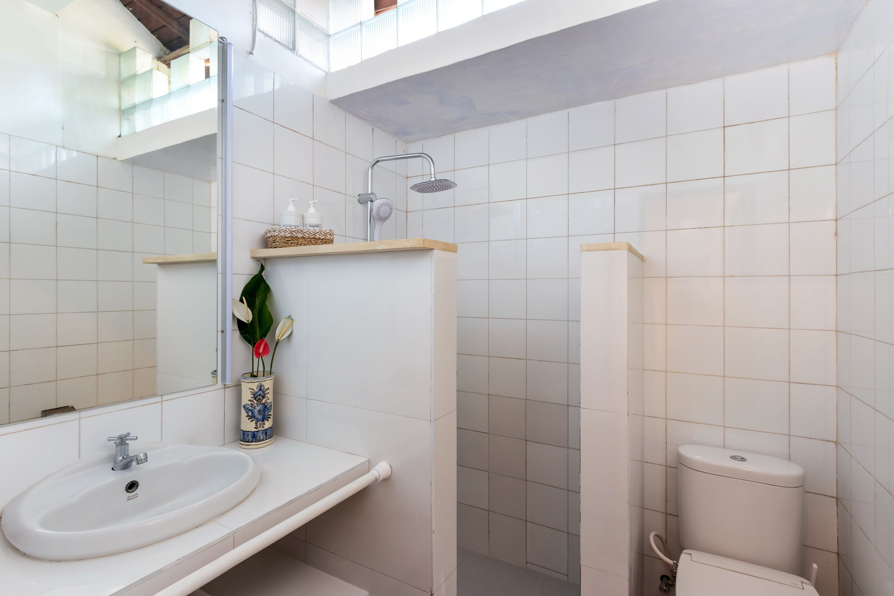 A bathroom with a white sink, a mirror, a shower, and a toilet.