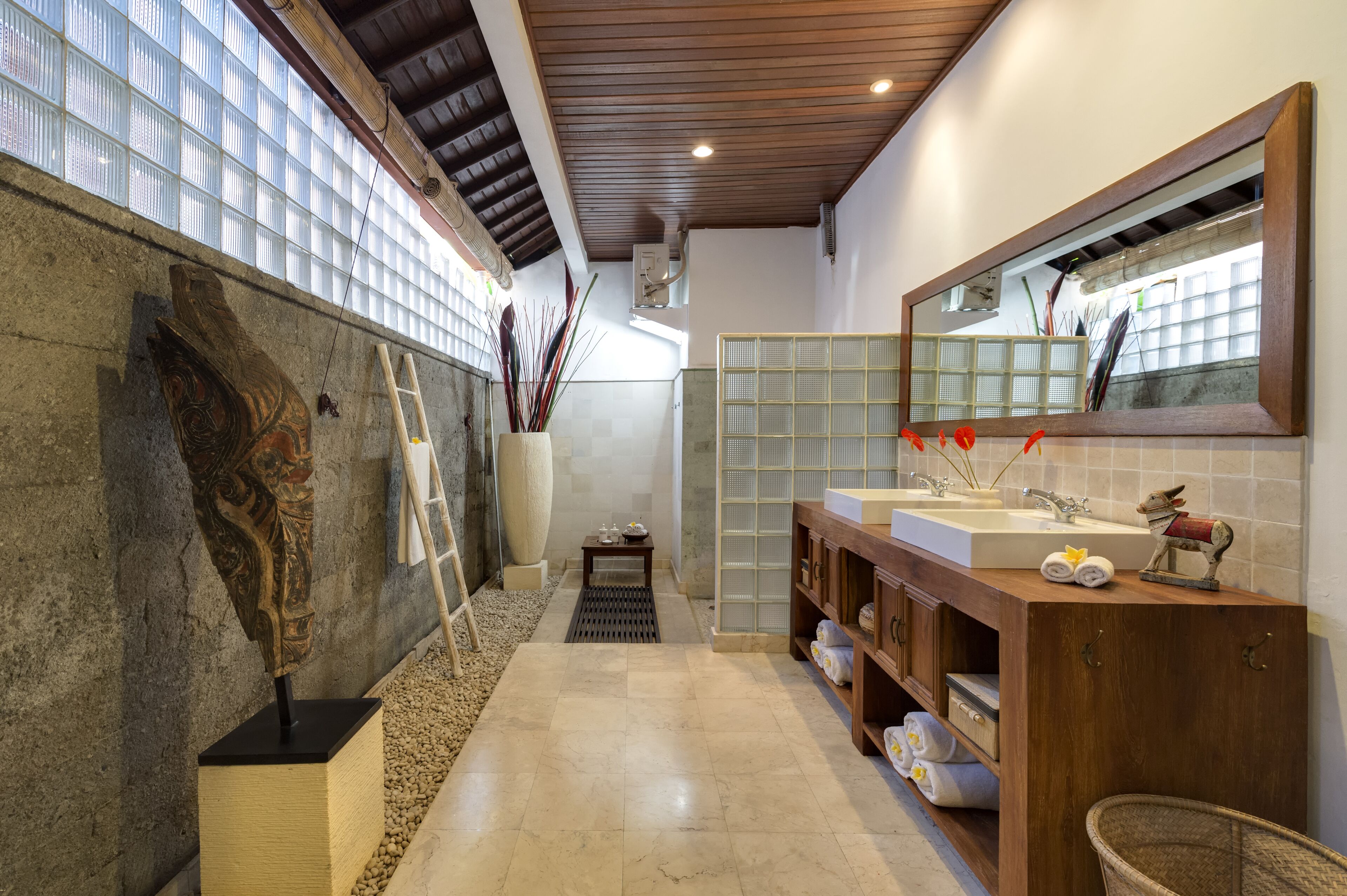 Un baño moderno con un espejo grande, dos lavamanos, un tocador de madera y una escultura decorativa de un pez.