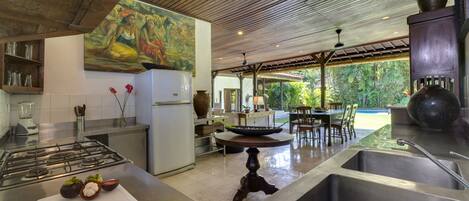 A modern kitchen with a central island, a dining area with a view, and a large painting on the wall.