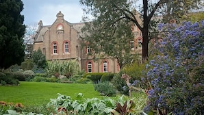 A large, historic building with a well-maintained garden and a prominent red brick facade. - Eltham Retreat Guest House (Eltham)